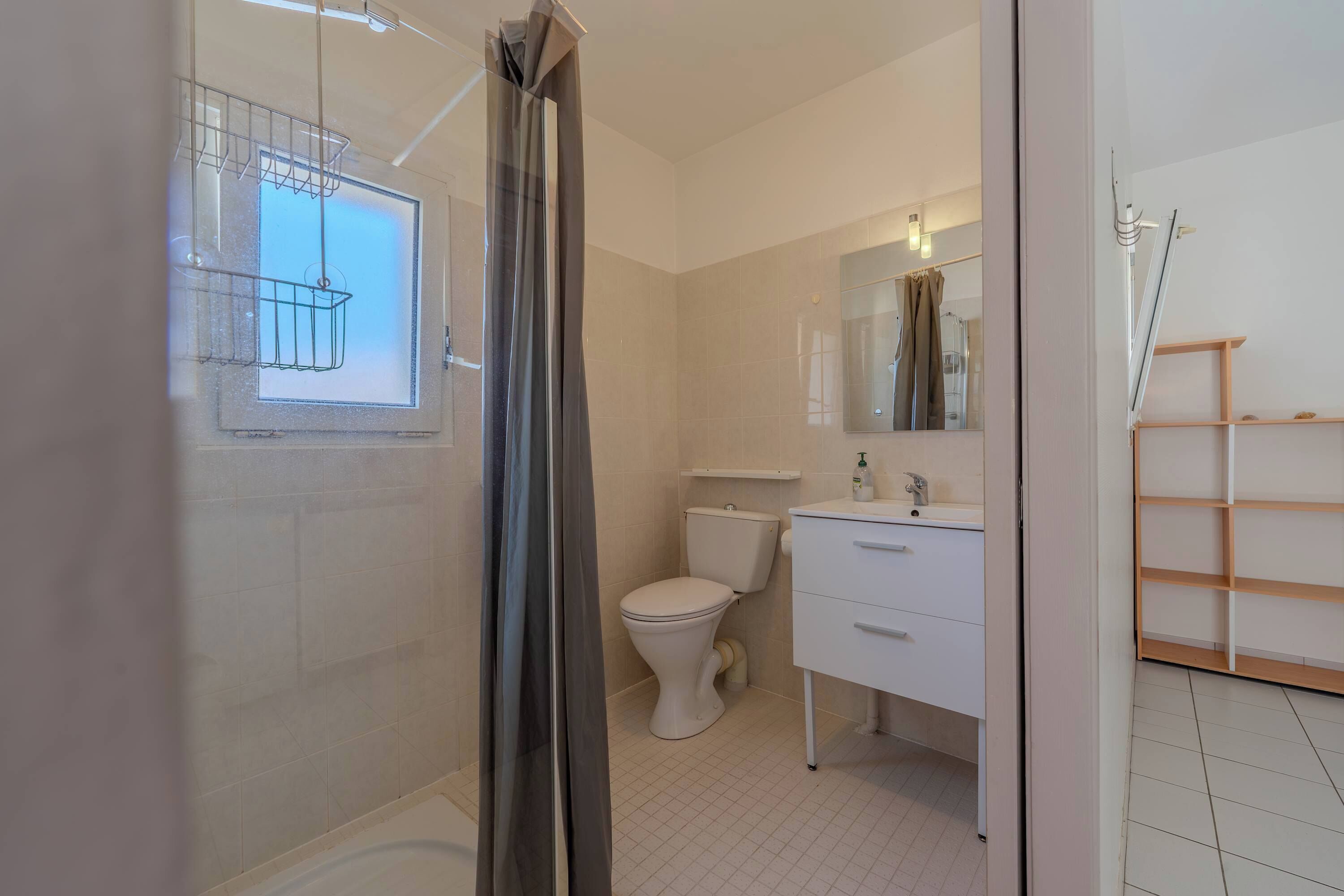 Un baño con inodoro, lavabo, espejo y zona de ducha.