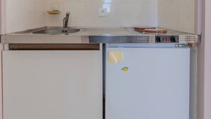 A compact kitchen with a sink, stove, and refrigerator. - Golden Waves Aparthotel - Kiwi Residence (Aytré)
