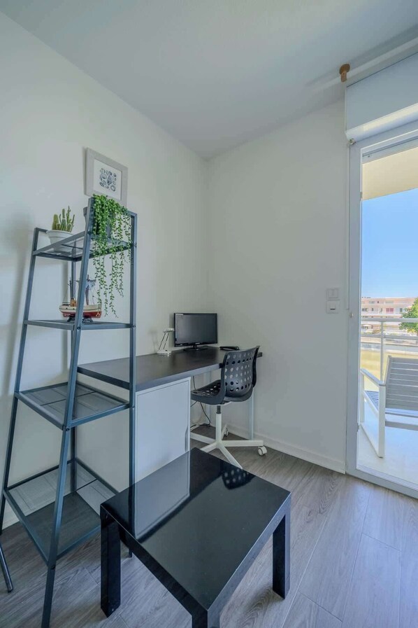 A modern, minimalist room with a desk, chair, and a black shelving unit. - Studio with a view of Lake La Sole (La Rochelle)