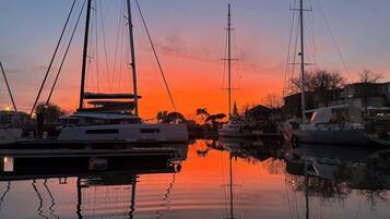 Un port esportiu amb diversos velers amarrats, reflectits en aigües tranquil·les durant el capvespre.