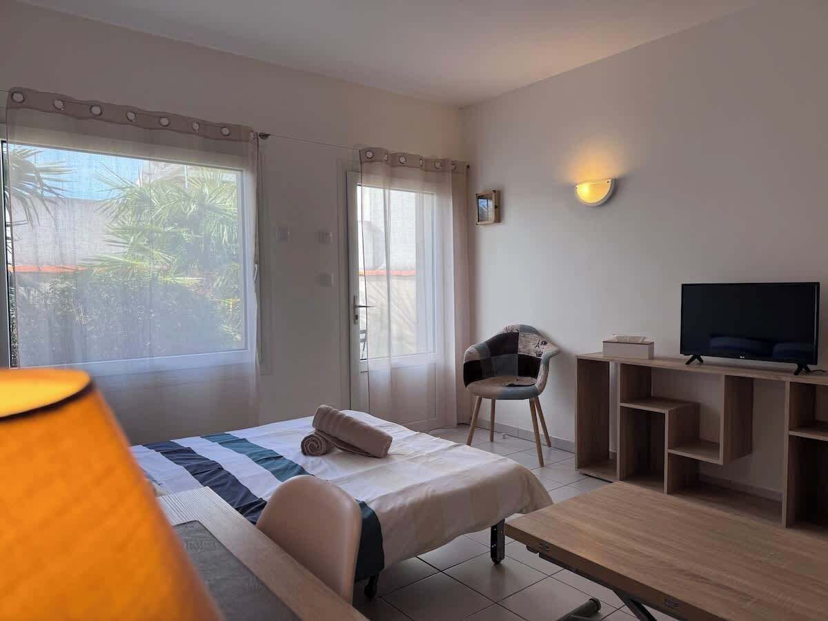 A hotel room with a bed, a chair, a TV, and a desk.