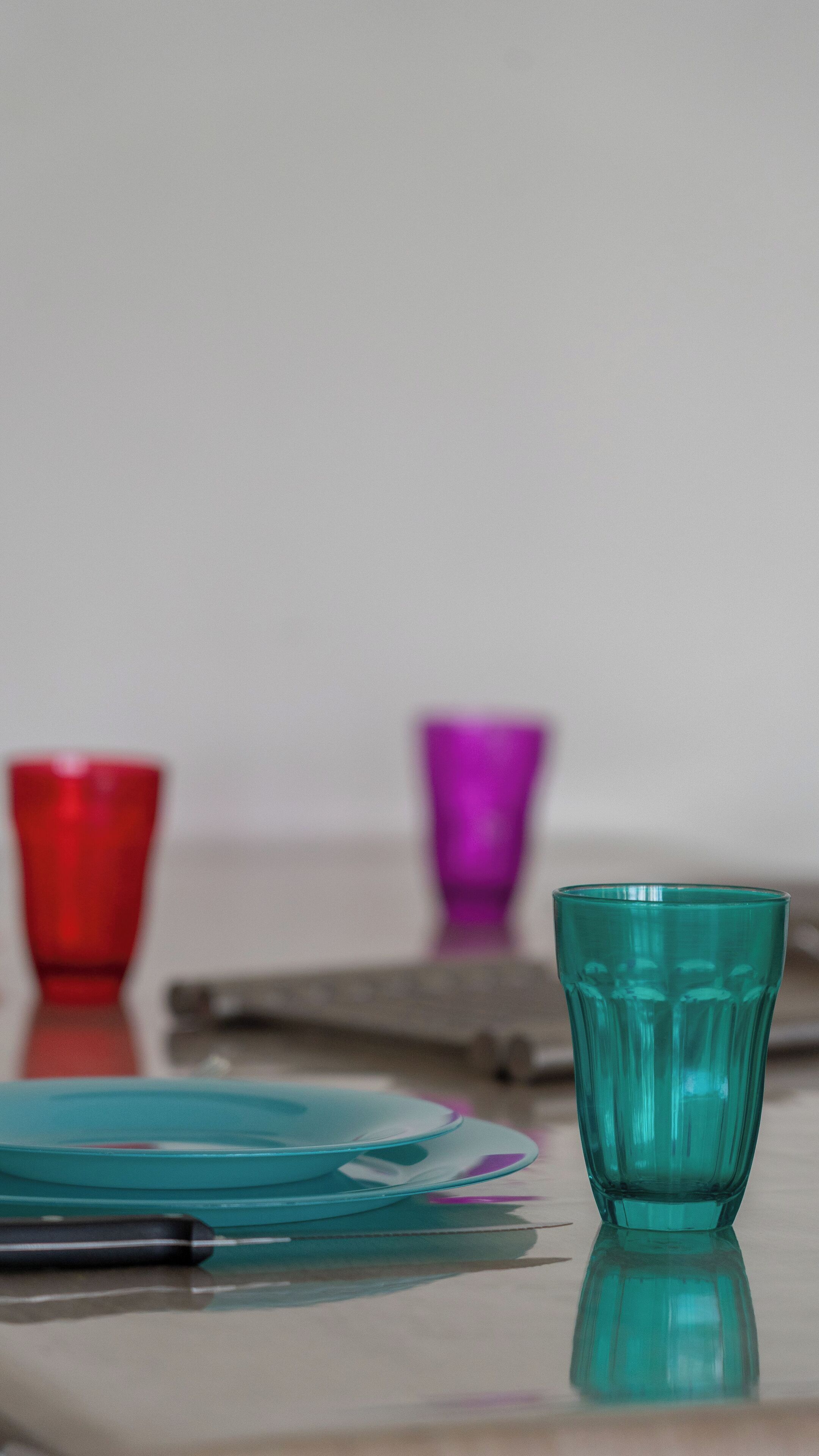 Uma mesa com três copos de vidro e uma caneta.