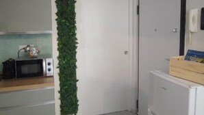 A kitchen with a microwave, a small refrigerator, and a wooden box on the counter. - SageGreən Flat (Genova)