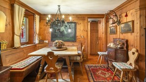 A wooden-paneled room with a dining table, benches, and a chandelier. - Angiolina Charming Apartment R&R (Cortina d´Ampezzo)