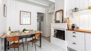 Et spiseområde med et træbord, stole og et hvidt skab med skuffer.