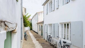 En smal gyde med hvide bygninger, cykler parkeret langs siderne og en brostensbelagt sti.