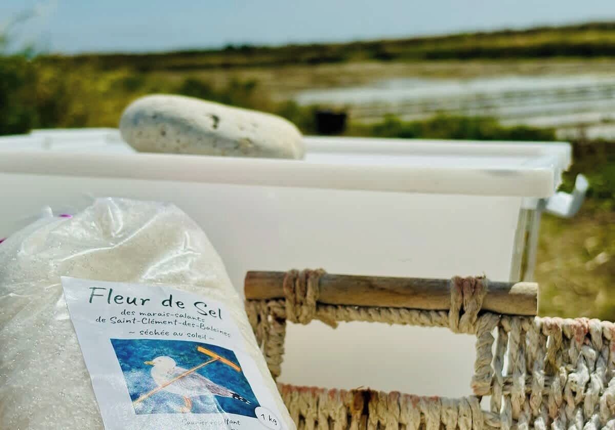 Un récipient blanc portant une étiquette indiquant « Fleur de sel » et un sac de sel placé à côté.