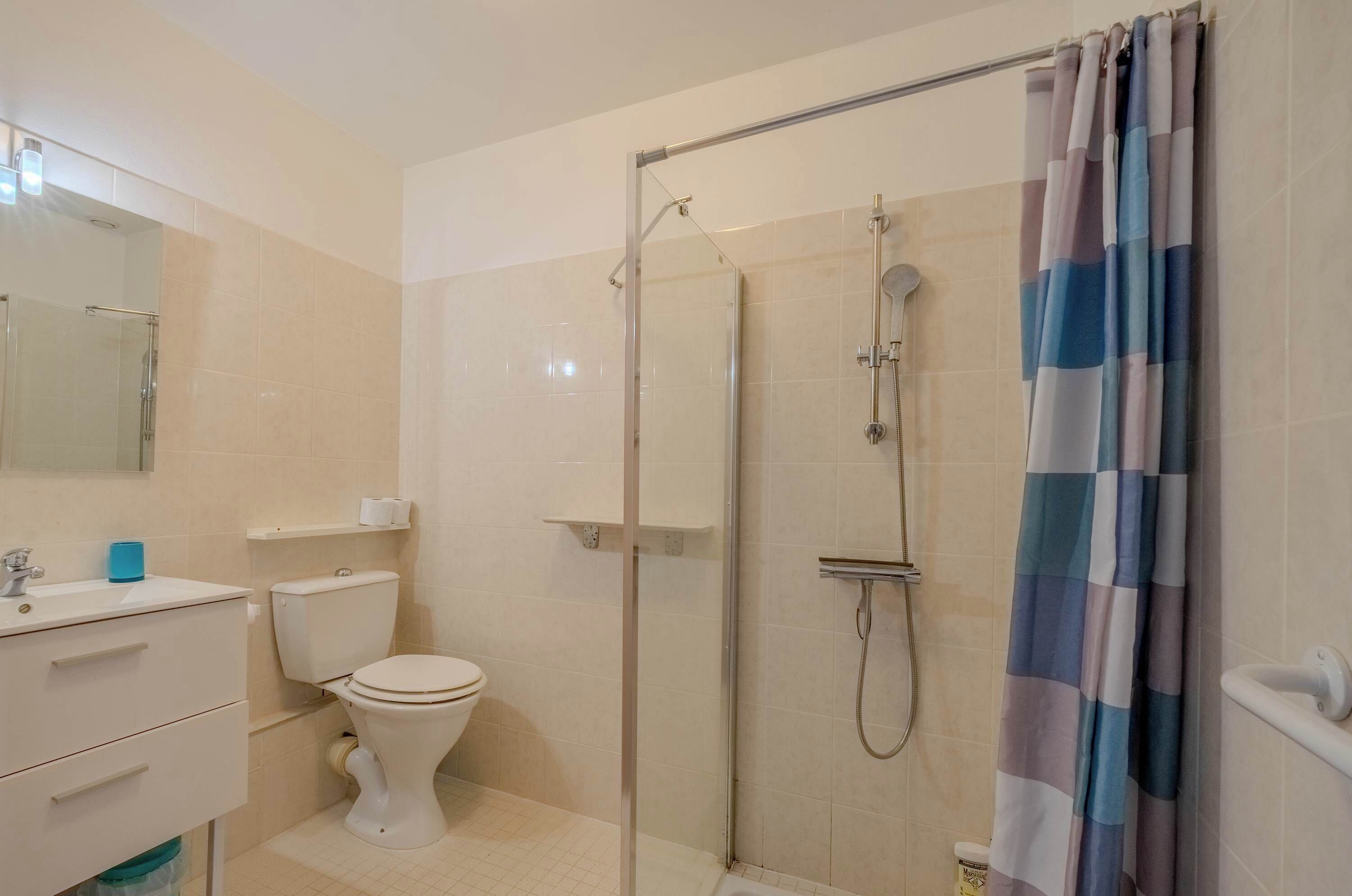 A bathroom with a toilet, sink, and shower area.