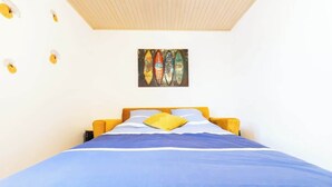 Un dormitorio con cama, almohadas y una obra de arte en la pared sobre la cama.