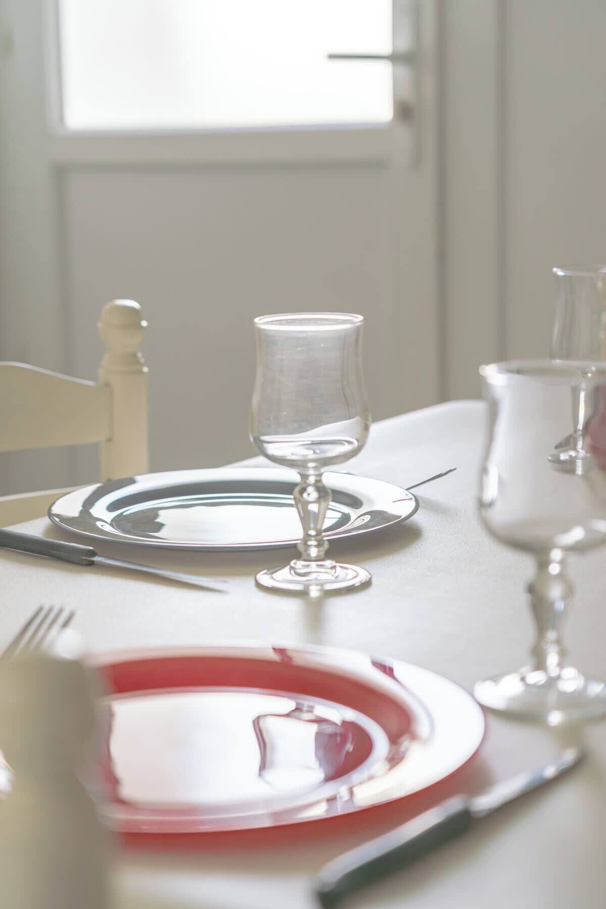 A dining table set with plates, cutlery, and wine glasses.