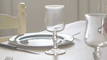 A dining table set with plates, cutlery, and wine glasses.