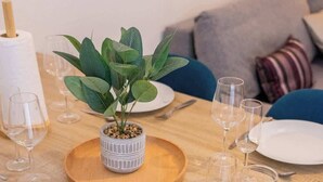 A dining table set with plates, cutlery, and wine glasses, with a potted plant and a candle holder on the table. - Appartement de l'ammonite (La Rochelle)