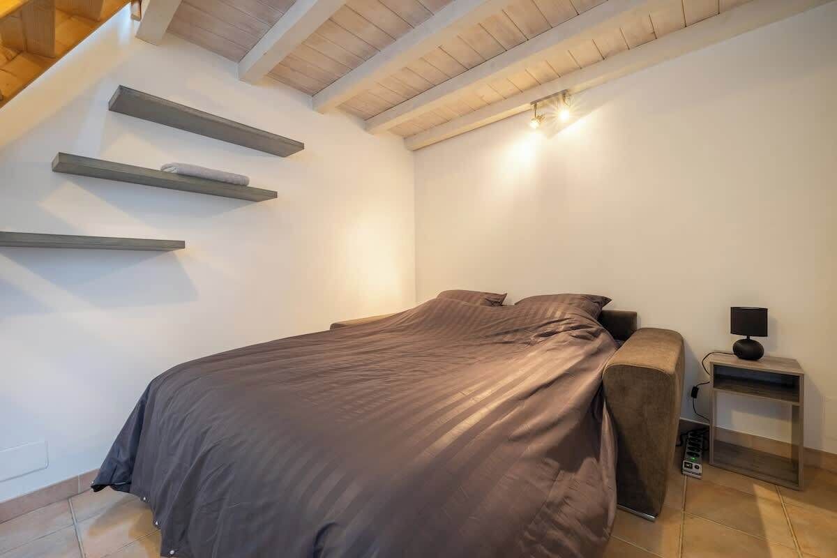 Une chambre à coucher comprenant un lit, une table de chevet et une étagère fixée au mur.
