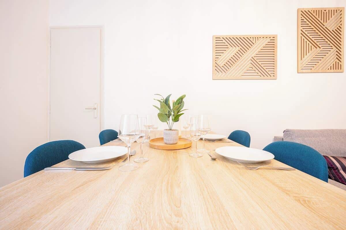A dining area with a wooden table, blue chairs, and a potted plant.