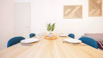 A dining area with a wooden table, blue chairs, and a potted plant.