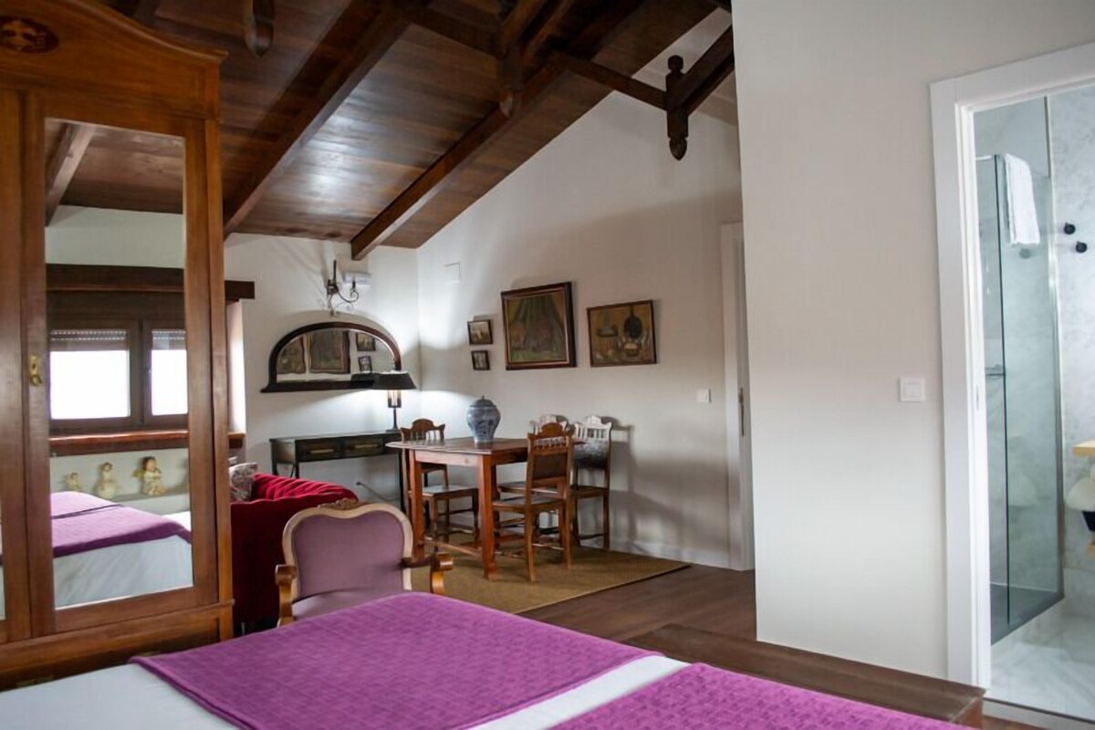 A room with a bed, a desk, a chair, a table, and a mirror.