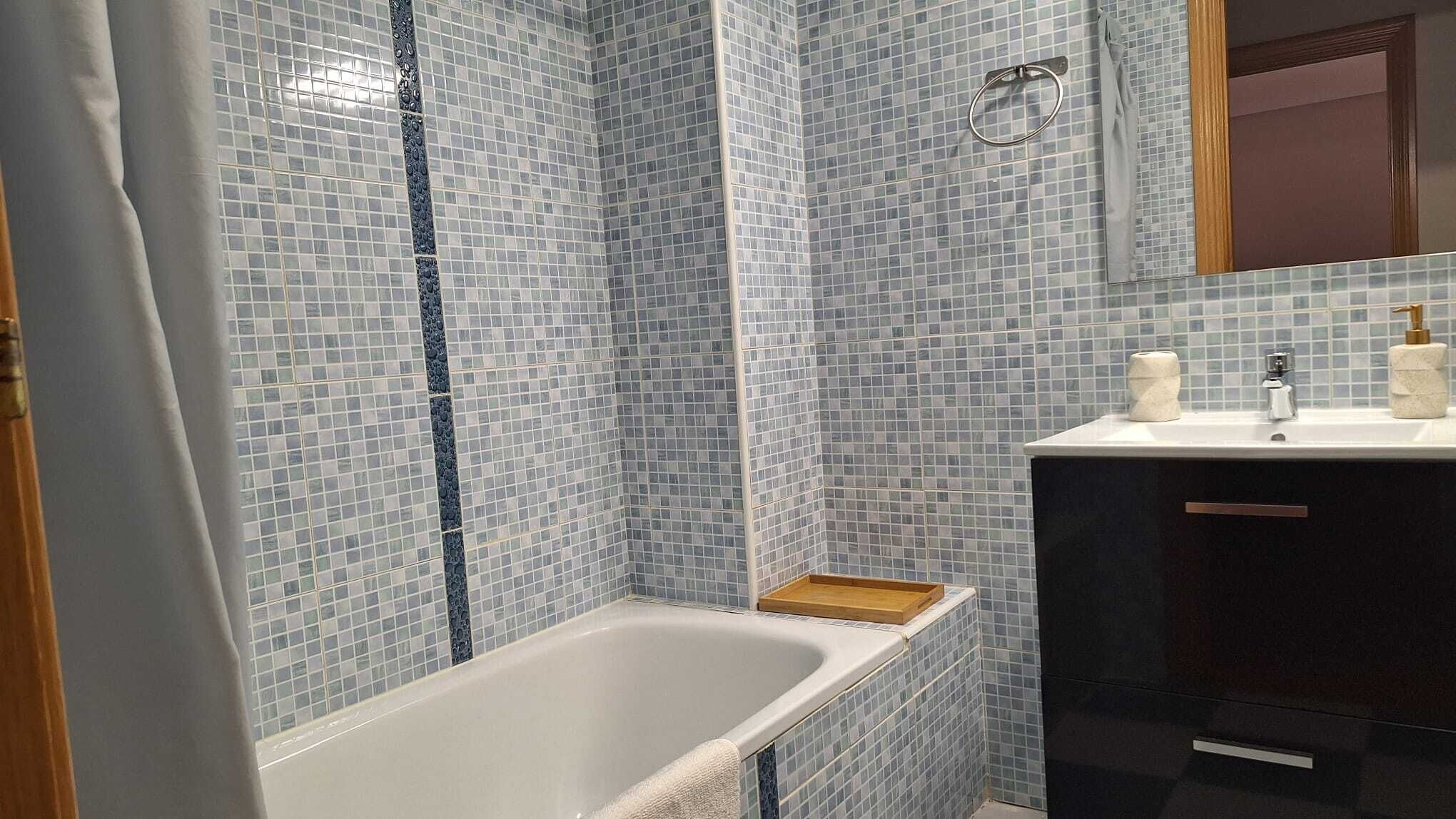 Un baño con bañera, lavamanos y espejo.