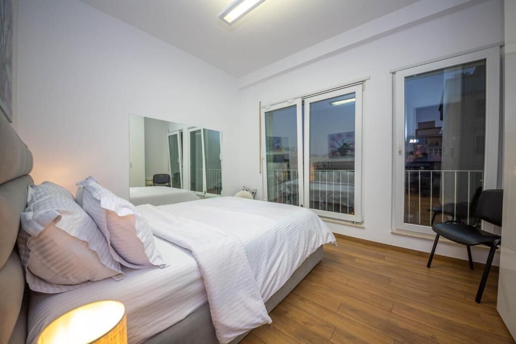Un dormitorio moderno con una cama grande, una silla y un balcón con puertas de vidrio.