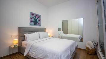 A bedroom with a bed, bedside tables, a lamp, a wall-mounted mirror, and a painting.