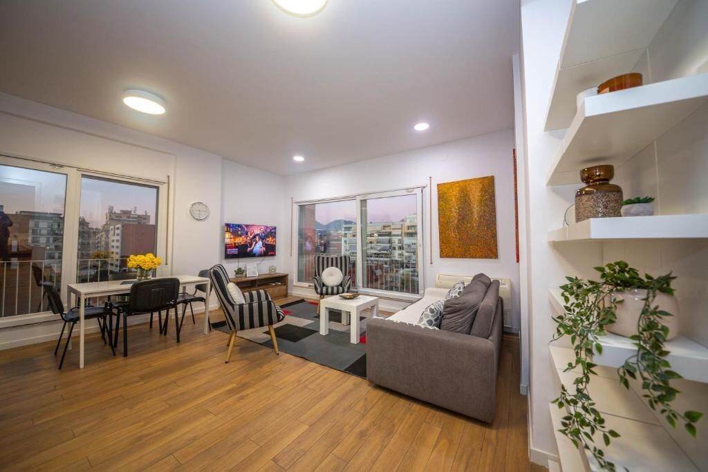 A modern living room with a dining area, large windows, and a city view.