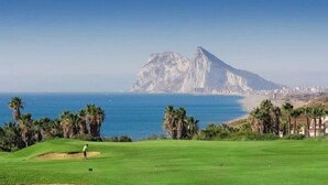 Un parcours de golf offrant une vue sur la montagne et la mer.
