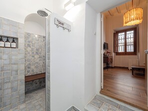 A bathroom with a shower, tiled walls, a bench, and a sign above the door. - El Conventillo de San Roque (San Roque)