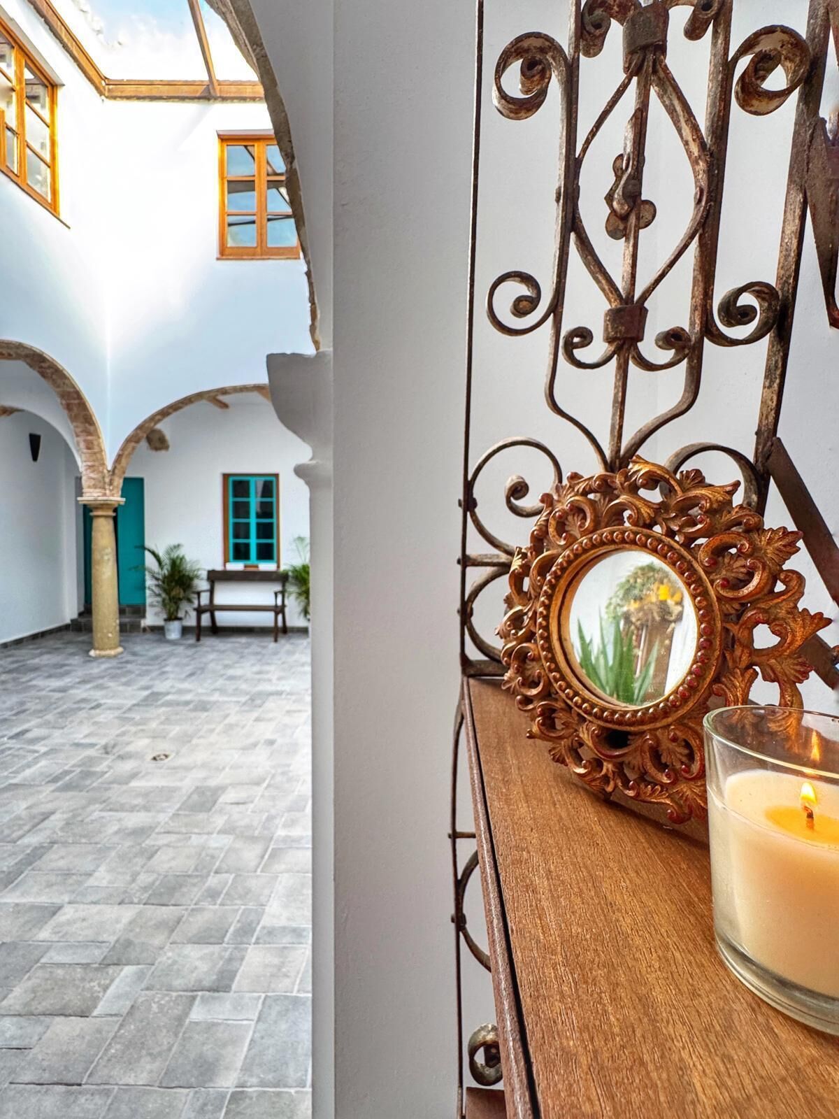 Un patio con un banco de madera, una vela y un espejo decorativo.