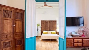 Une chambre à coucher avec un lit, un ventilateur de plafond, une télévision et des meubles en bois.