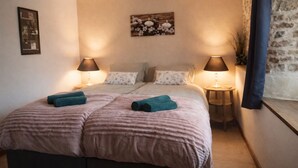 A double bed with two pillows, two bedside tables with lamps, and a wall-mounted picture.