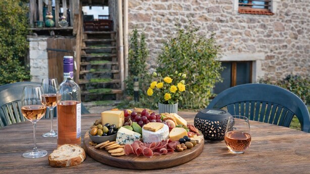 A wooden table with a charcuterie board, wine glasses, and a bottle of rosé wine.