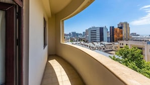 Un balcon offrant une vue sur le paysage urbain, avec différents bâtiments et un ciel dégagé.