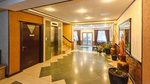 A hotel lobby with a check-in desk, a staircase, and potted plants. - Diplomat Palace Hotel (Baku)