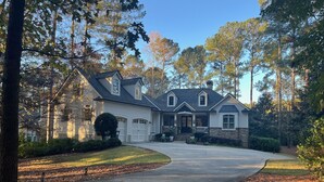 A two-story house with a stone foundation, a front porch, and a driveway leading to the garage. - Lakefront Retreat for Masters week 2026
Sleeps12
Boat use with separate contract (Greensboro)