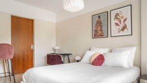 A bedroom with a large bed, a desk, two chairs, and two framed artworks on the wall. - Studio 4* with balcony and parking in Bel Air (Luxembourg)