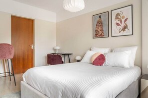 A bedroom with a large bed, a desk, two chairs, and two framed artworks on the wall. - Studio 4* with balcony and parking in Bel Air (Luxembourg)