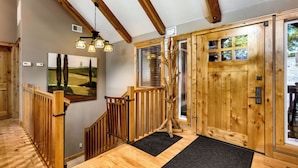 Una escalera de madera con un felpudo negro, una puerta de madera con ventanas y un cuadro en la pared.