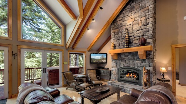 Una sala de estar acogedora con chimenea de piedra, sofás de cuero y un televisor.