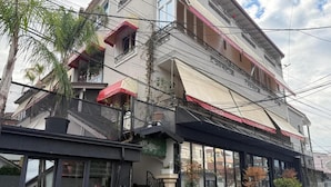 A multi-story building with balconies, a covered entrance, and a gated area with potted plants. - La Villa Bnb (Tirana)