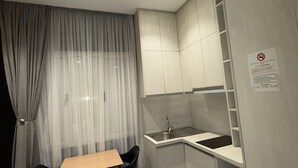 A compact kitchen with a dining area, including a table and chairs, a sink, and a cabinet. - La Villa Bnb (Tirana)