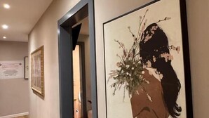 A hallway with framed artwork on the walls, wooden flooring, and a door leading to another room. - La Villa Bnb (Tirana)