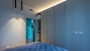 A bedroom with a bed, a wardrobe, and a bathroom visible through an open door. - Sanremo Belle Epoque Apartment by Wonderful Italy (Sanremo)