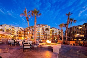 Un patio de hotel al anochecer con asientos al aire libre y palmeras.