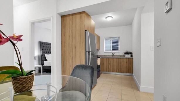 Eine moderne Küche mit Holzschränken, einem Edelstahlkühlschrank und einem Fenster mit Jalousien.