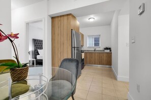 Eine moderne Küche mit Holzschränken, einem Edelstahlkühlschrank und einem Fenster mit Jalousien.