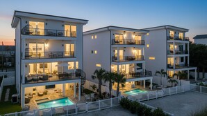 A multi-story residential building with balconies, a swimming pool, and a white fence. - Beach Two: Style Meets the Shore w/ Pool and Spa (Treasure Island)
