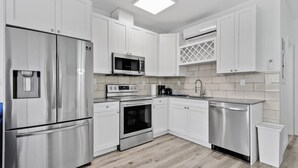 Uma cozinha moderna com armários brancos, eletrodomésticos de aço inoxidável e painel de azulejos.