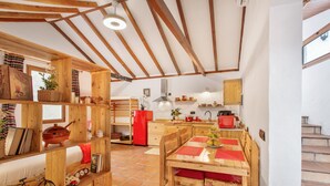 A rustic kitchen with wooden beams, a dining table, and a red refrigerator. - Vacation Apartment 'Casa Rural Ruta Del Tajinaste Azul' with Sea View, Wi-Fi & Air Conditioning (Valsequillo)