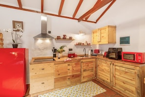 A kitchen with wooden cabinets, a red refrigerator, a microwave, and a sink. - Vacation Apartment 'Casa Rural Ruta Del Tajinaste Azul' with Sea View, Wi-Fi & Air Conditioning (Valsequillo)