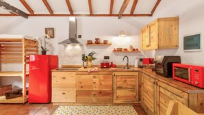 A kitchen with wooden cabinets, a red refrigerator, a microwave, and a sink. - Vacation Apartment 'Casa Rural Ruta Del Tajinaste Azul' with Sea View, Wi-Fi & Air Conditioning (Valsequillo)