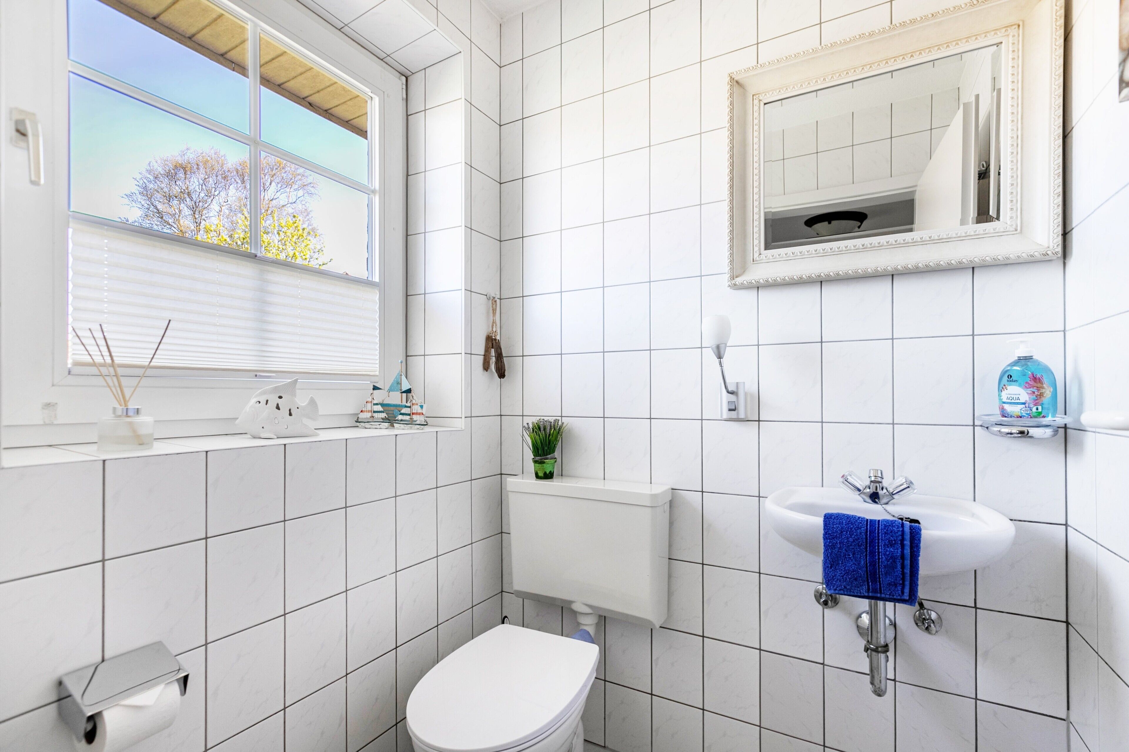 Une salle de bain comprenant des toilettes, un lavabo, un miroir et une fenêtre.